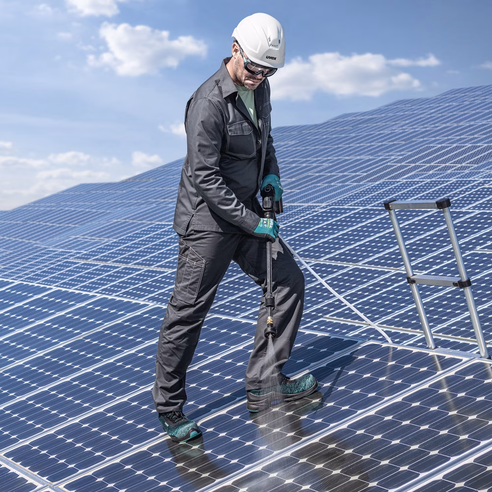 man cleaning solar panels, wearing helmet head protection and uvex safety boots